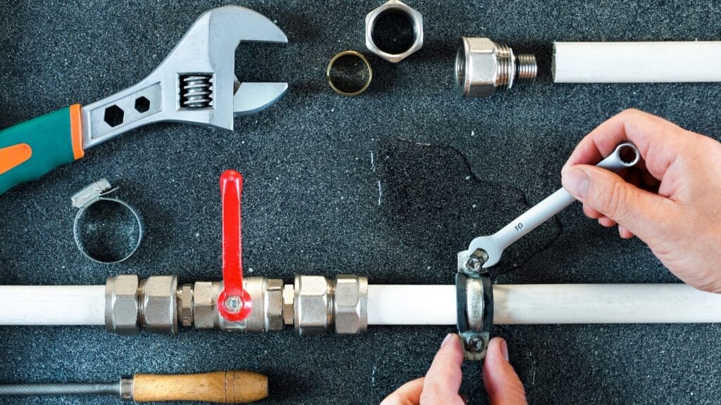 Plumber repairing a pipe valve with an adjustable wrench in Brentwood