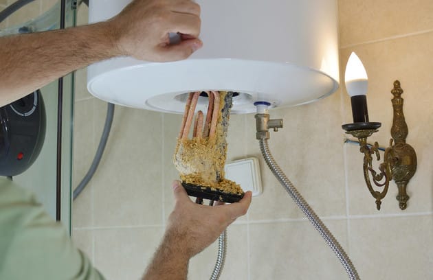 Technician removing mineral buildup from a water heater in Brentwood