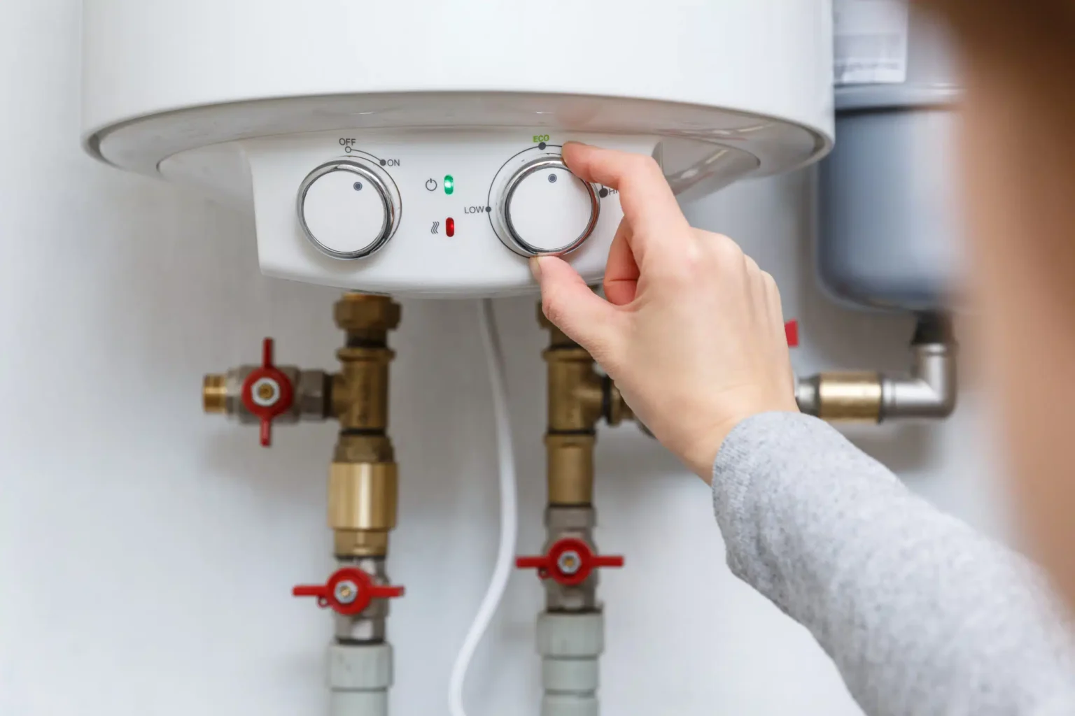 Homeowner adjusting the temperature controls on a water heater in Brentwood